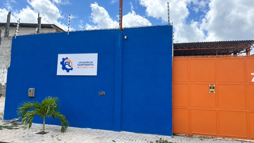 Fachada do novo galpão da F&L Locações, com muro azul e portão laranja